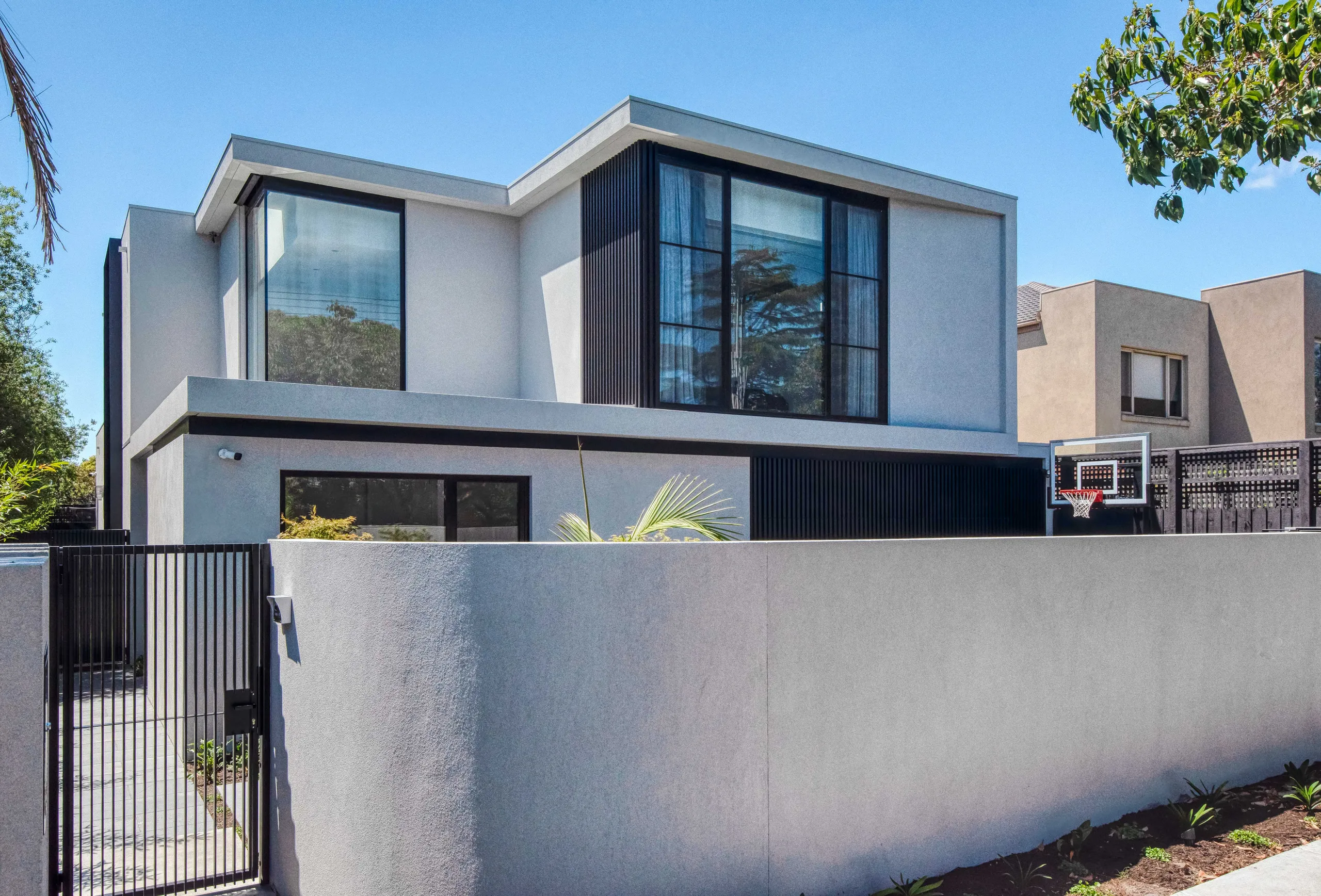 Street elevation of a rendered two-storey home set behind a solid front wall