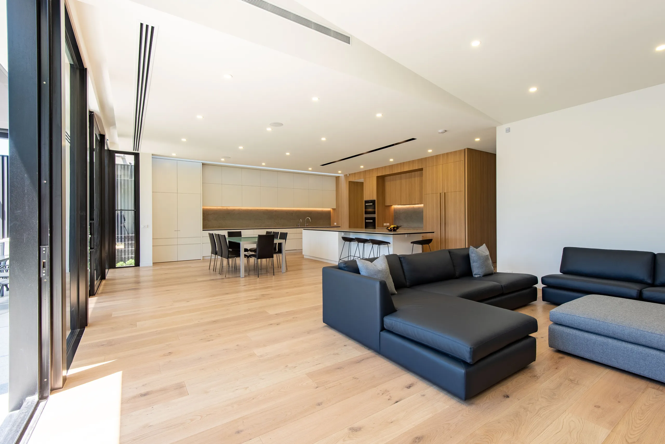 Living and dining seen from the far end, with full-height glazing to the garden