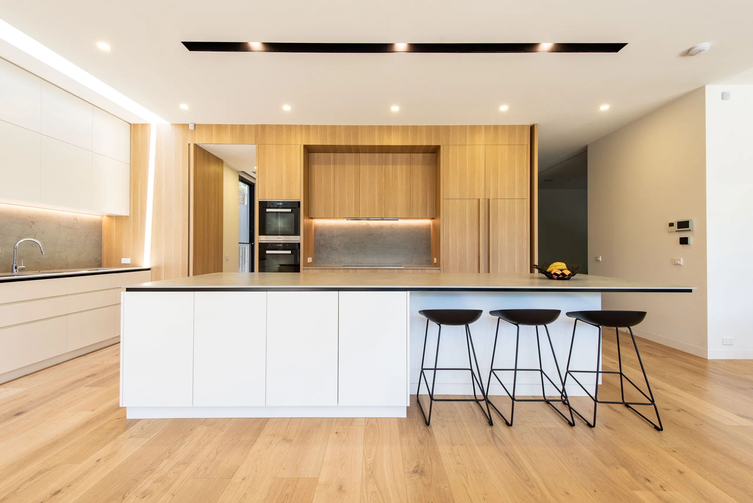 Kitchen with a stone-topped island, timber joinery and integrated appliances
