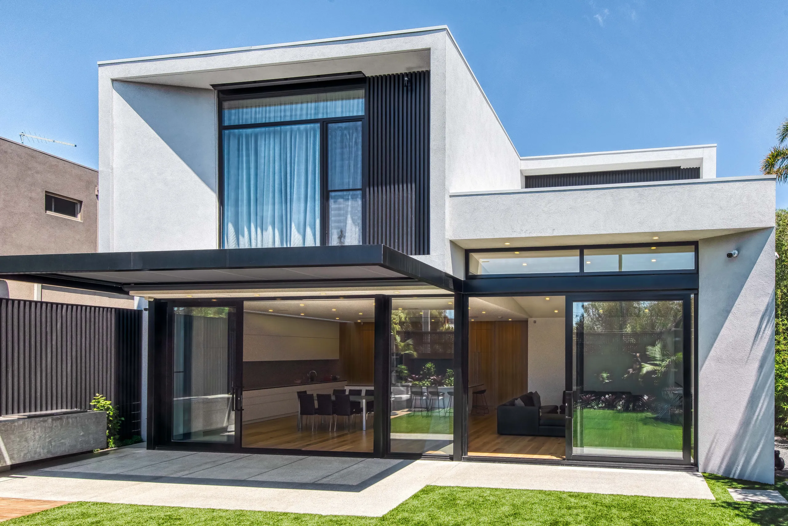 Rear elevation opening onto lawn through full-height sliding glazing